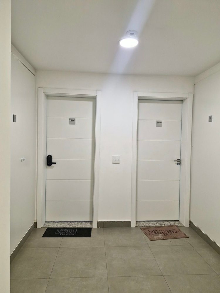 Duas portas brancas com filetes horizontais instaladas em corredor de edifício, com puxadores e numeração